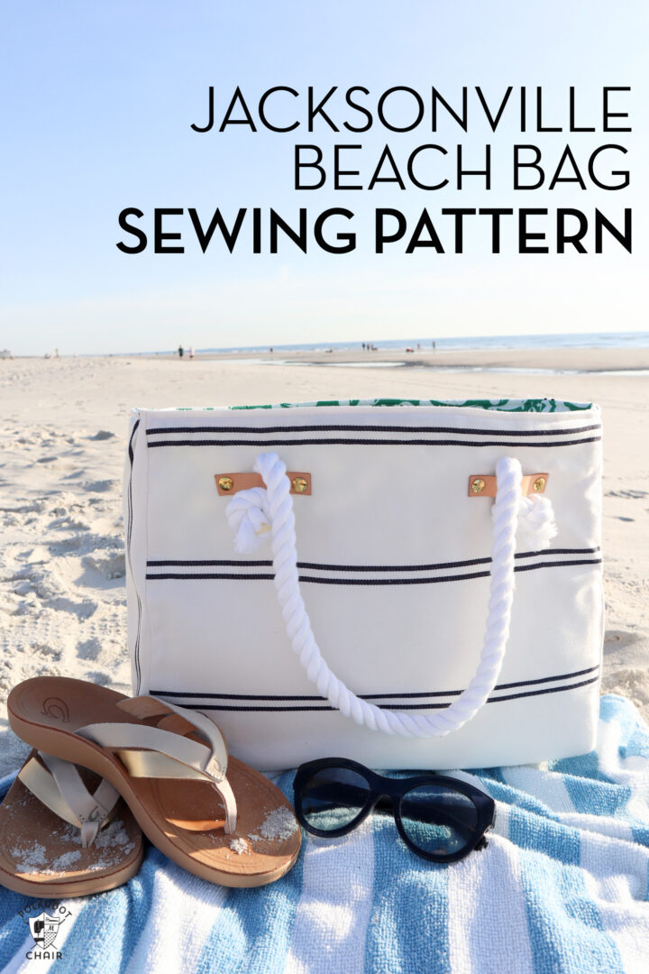 photo of a white and blue beach bag on beach with sandals and towel.