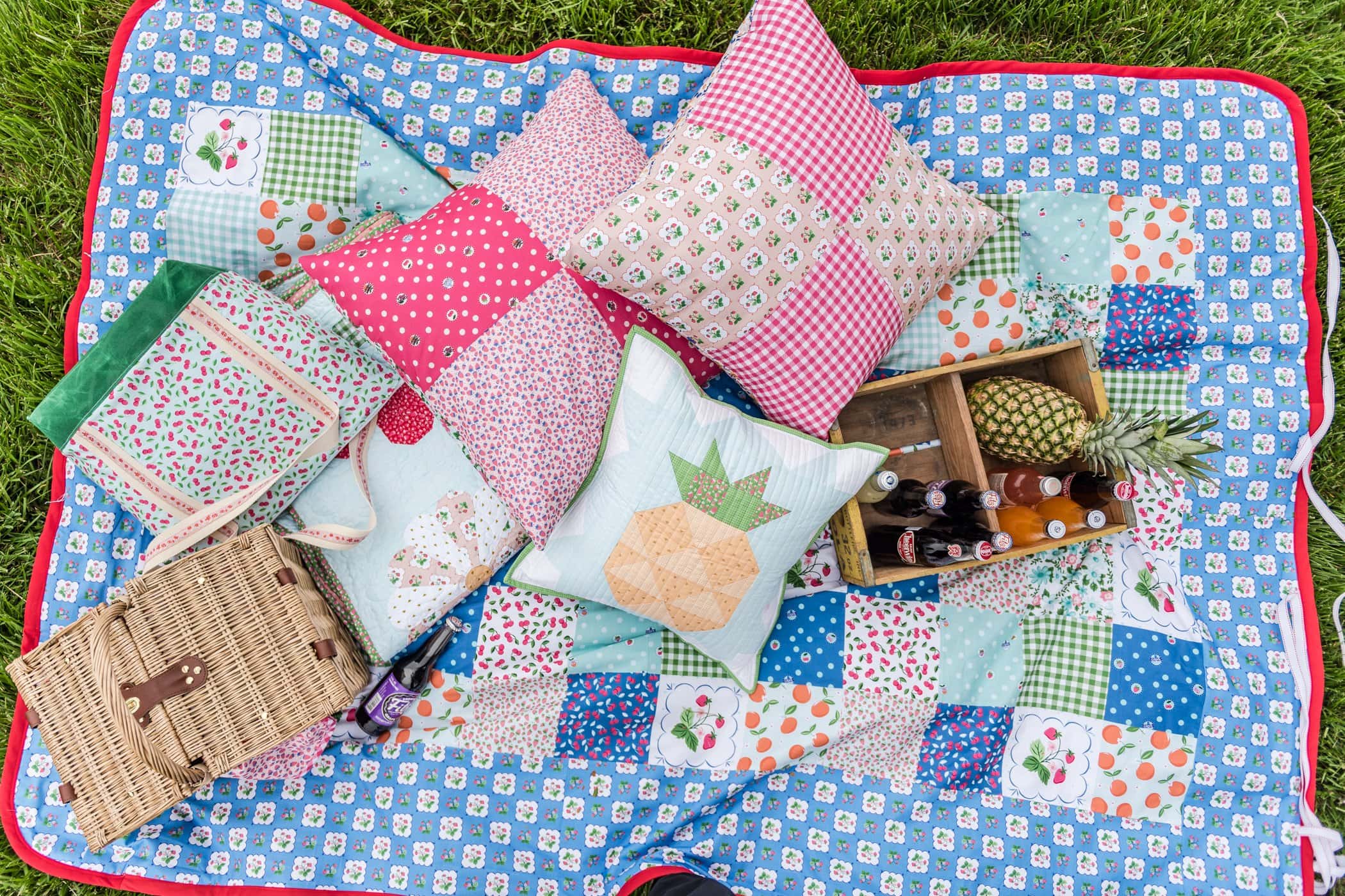 colorful pillows and picnic essentials on blanket outdoors