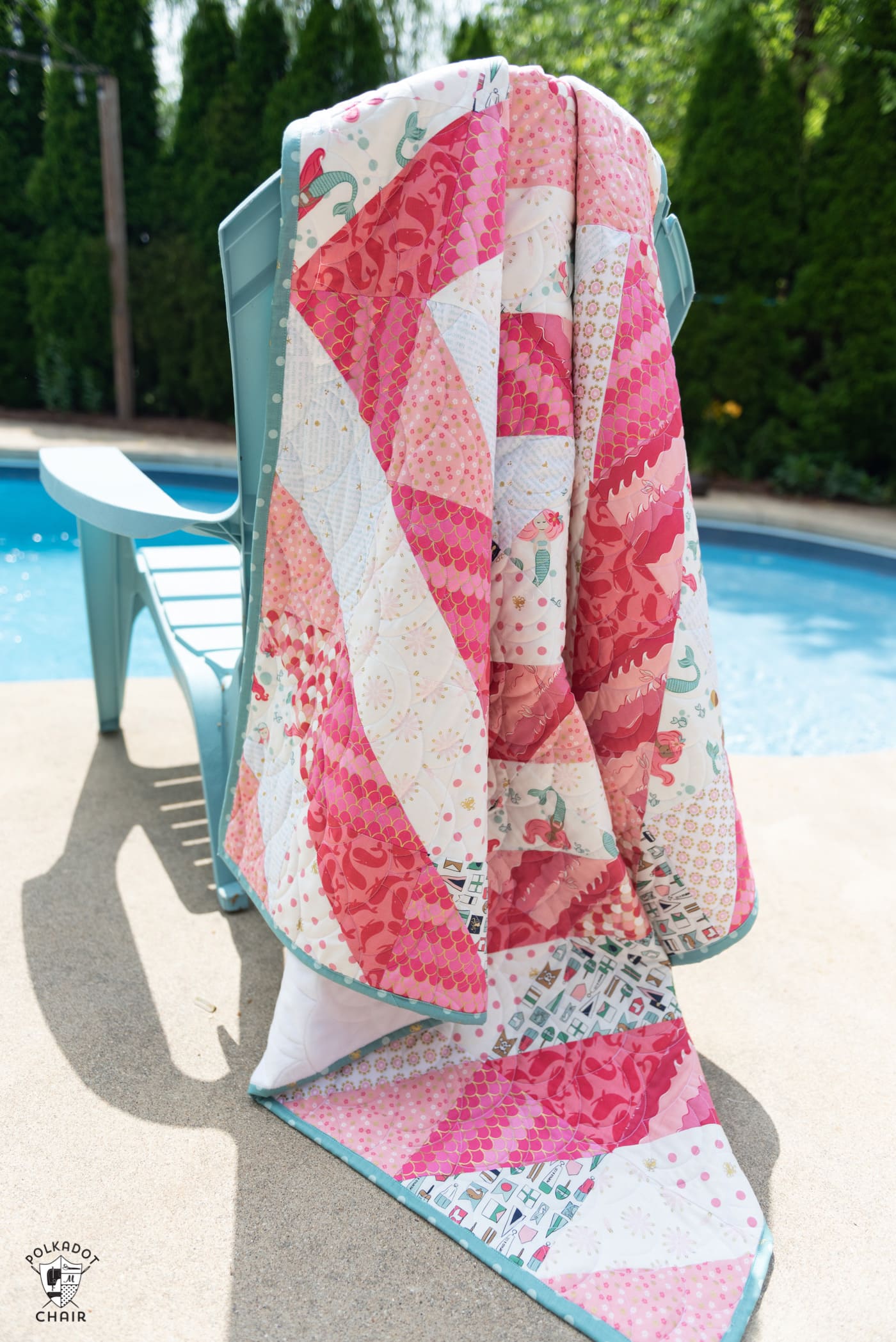 coral and white quilt draped over chair by pool