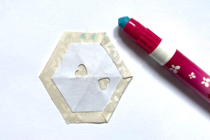 glue stick and hexagon pieces on white table