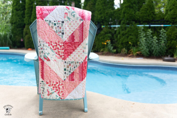 coral and white quilt draped over chair by pool