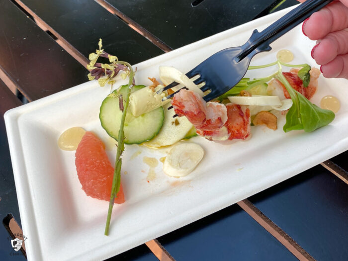 plate with poached lobster & veggies on black table