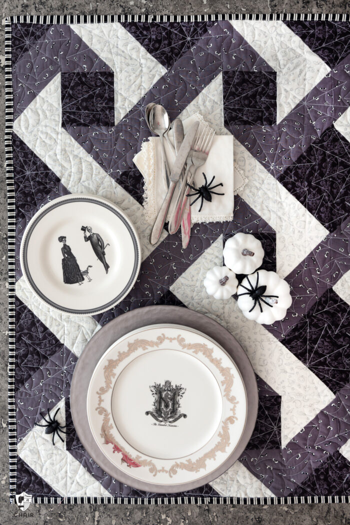 Halloween table setting with gray and black quilted table topper and white plates