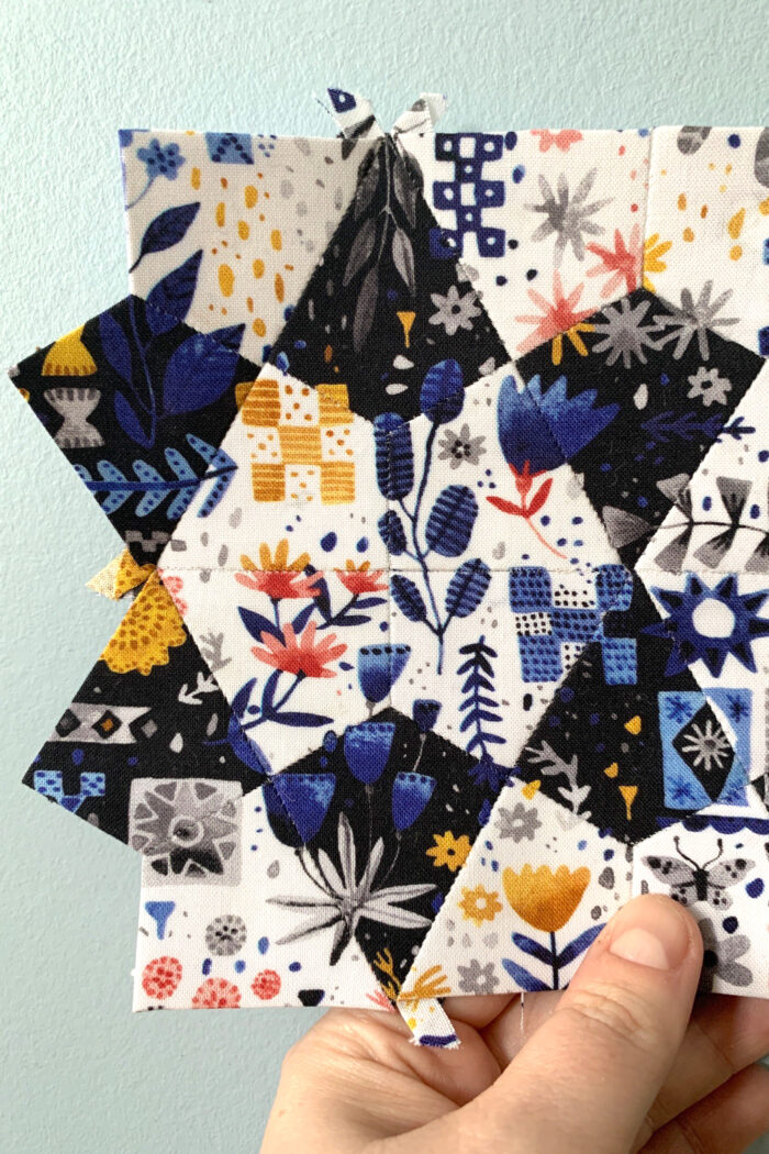 colorful hand pieced quilt block in front of blue wall
