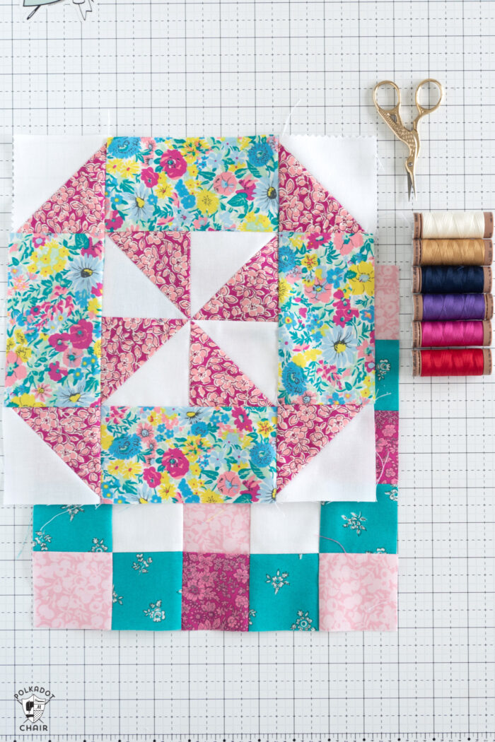 pink, blue, aqua and white quilt block and colorful thread on white cutting mat