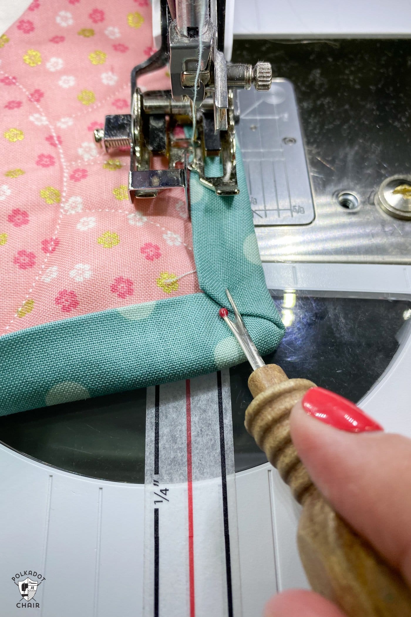 seam ripper holding fabric in place on sewing machine