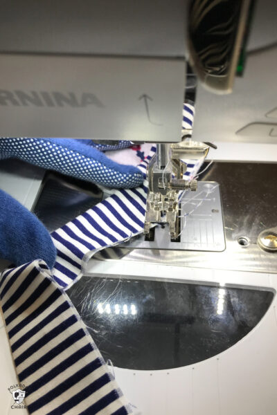 gloved hand holding a quilt under a sewing machine