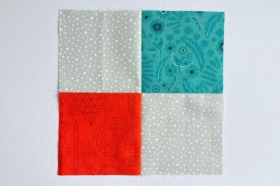 aqua, blue, & orange quilt blocks on white table