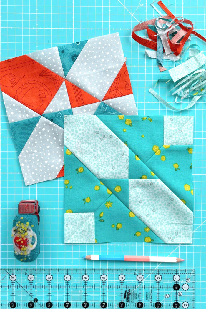 aqua, blue, & orange quilt blocks on dark aqua cutting mat