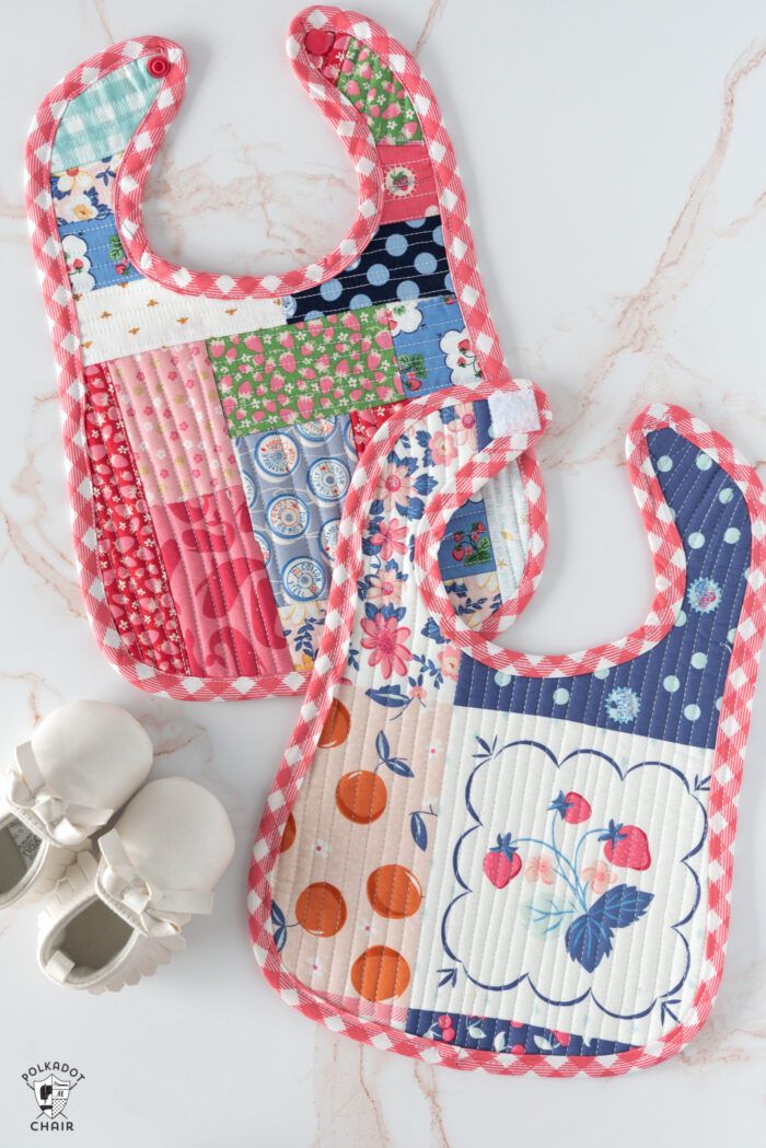 colorful scrappy baby bib on white marble tabletop with shoes