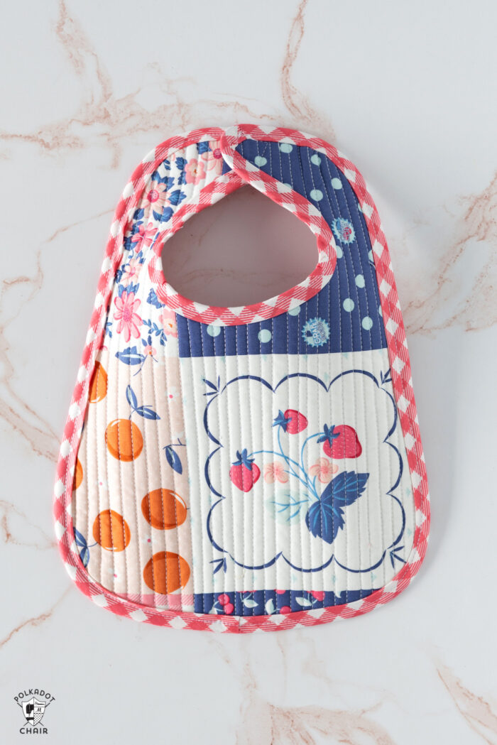 colorful scrappy baby bib on white marble tabletop