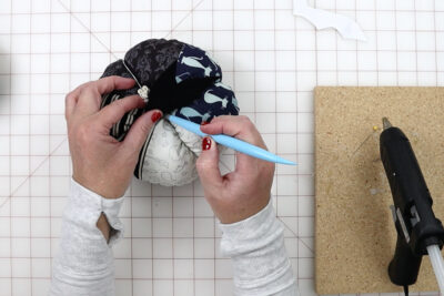 hands constructing fabric pumpkin with tools on white cutting mat