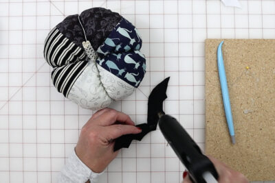 hands constructing fabric pumpkin with tools on white cutting mat