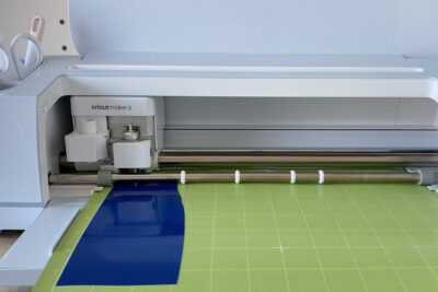 cricut machine with green cutting mat and blue vinyl