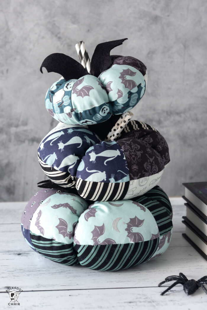 stack of fabric pumpkins on white table with gray background