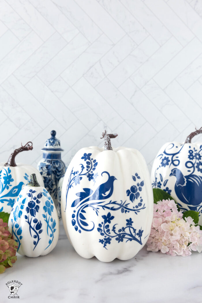 a collection of blue and white pumpkins on a white counter top with flowers