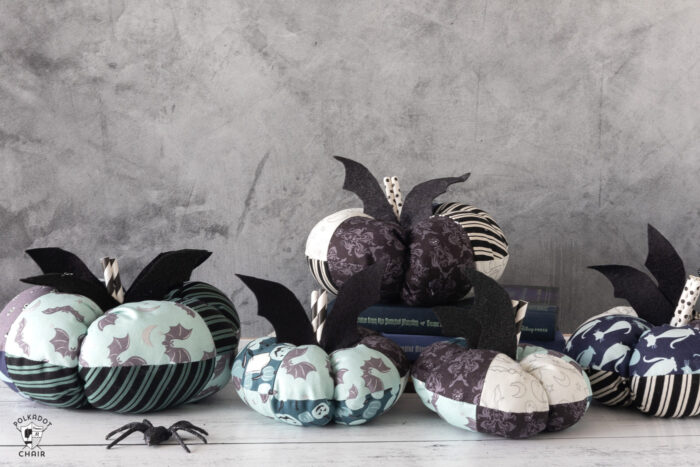 stack of fabric pumpkins on white table with gray background