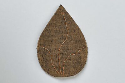 brown fabric leaf with needle and thread on white table