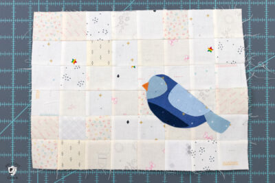 blue bird sewn to patchwork grid of white and cream squares