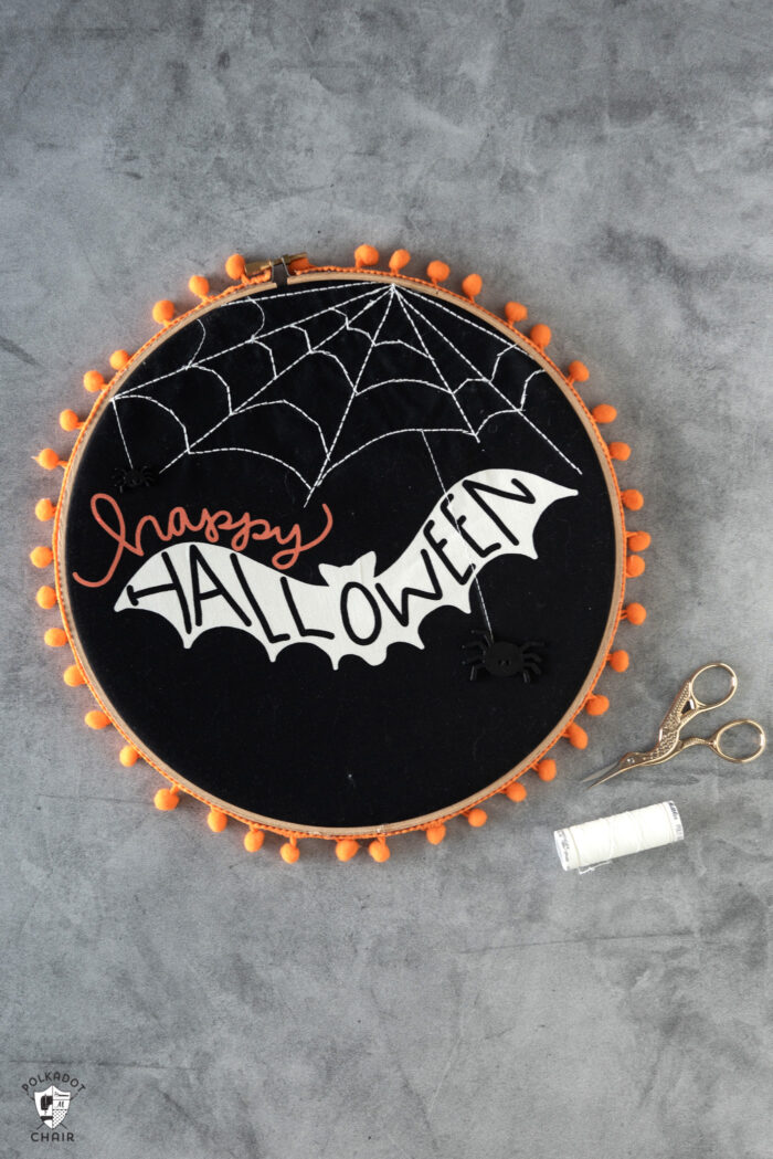 black fabric embroidery hoops on gray table with orange pom pom trim