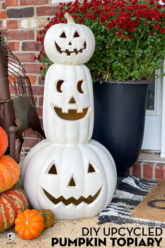 stack of white plastic pumpkins on front porch with red mums in urn 