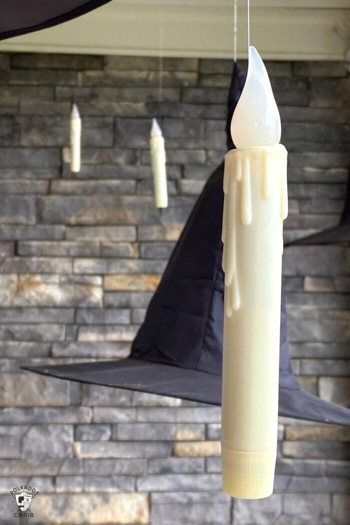 LED candles floating on front porch with black witch hats
