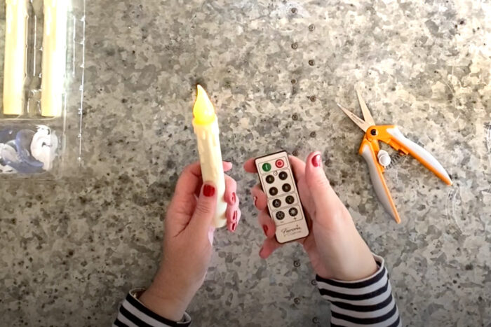 hands holding LED candle and remote