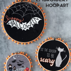 3 black fabric embroidery hoops on gray table with orange pom pom trim