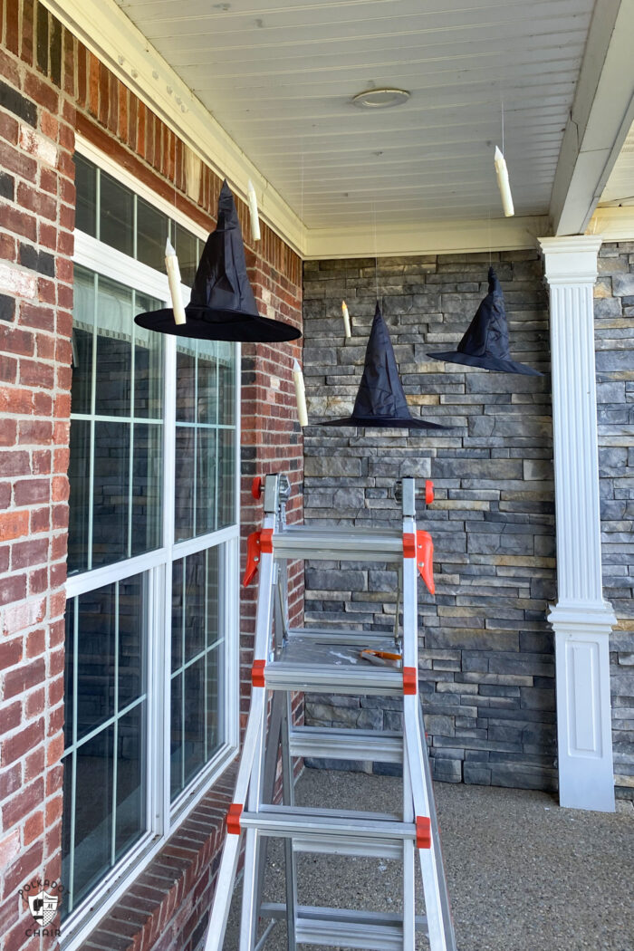 LED candles floating on front porch with black witch hats