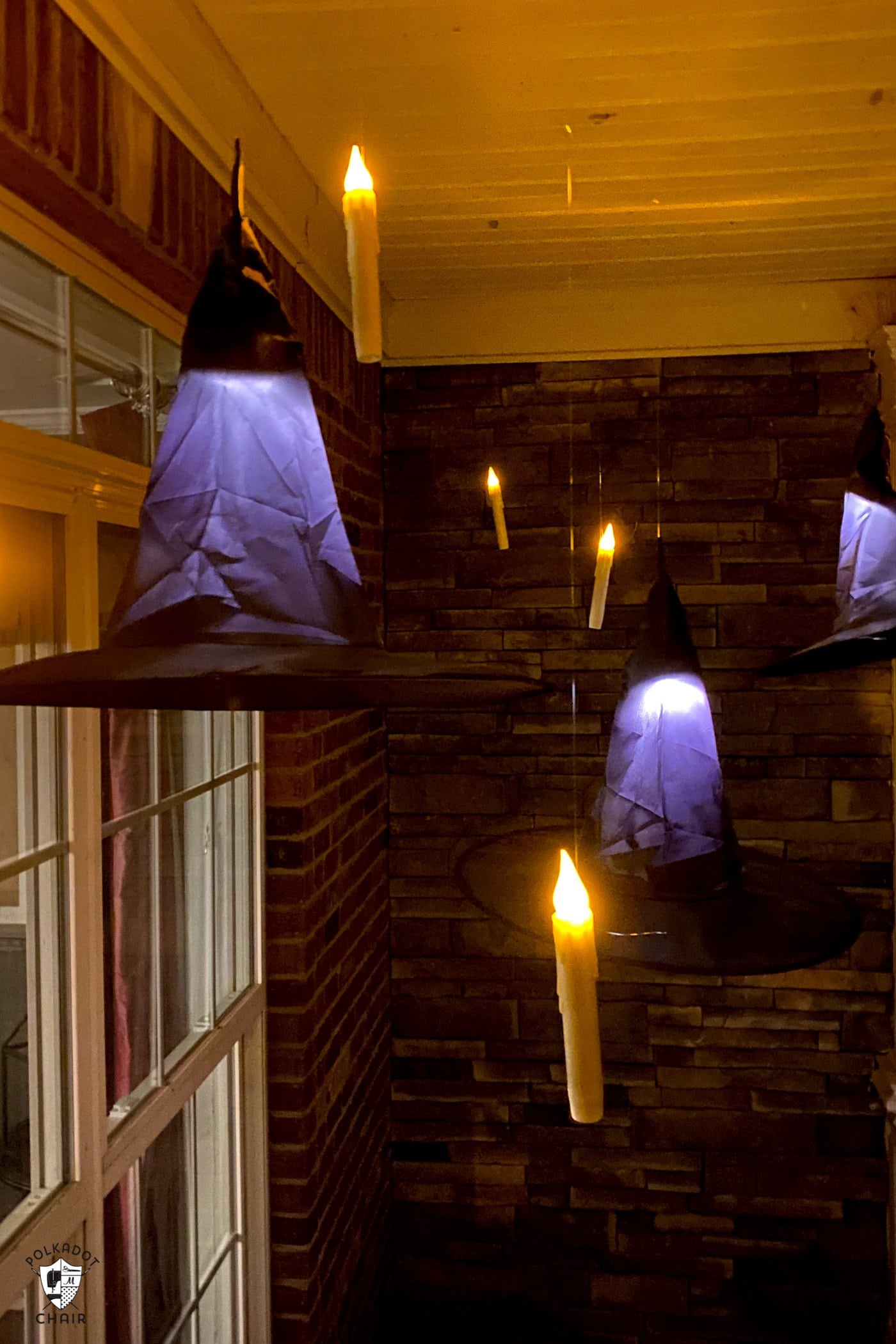 LED candles floating on front porch with black witch hats at night