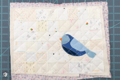 blue bird sewn to patchwork grid of white and cream squares