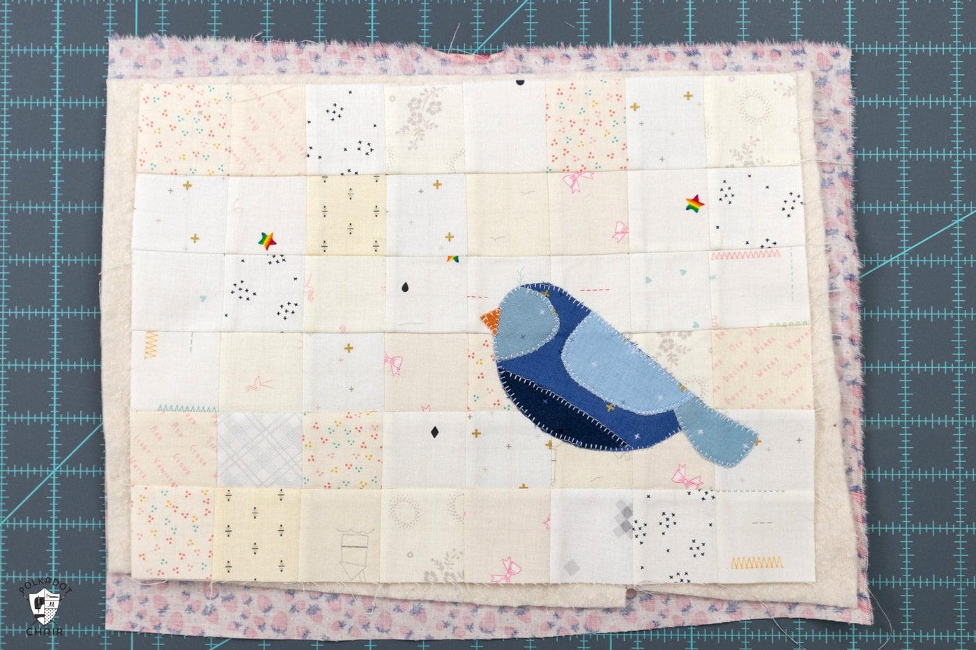 blue bird sewn to patchwork grid of white and cream squares