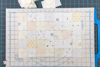 cream and white squares of fabric laid out on portable cutting board
