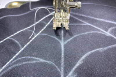 Sewing machine stitching straight lines on black fabric