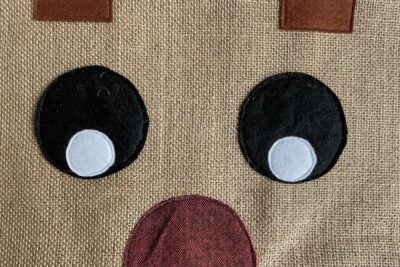 fabric sewn to burlap in shape of reindeer eyes nose and antlers