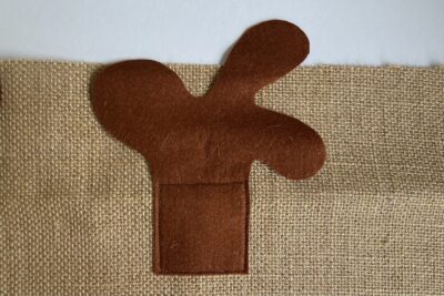 fabric sewn to burlap in shape of reindeer eyes nose and antlers