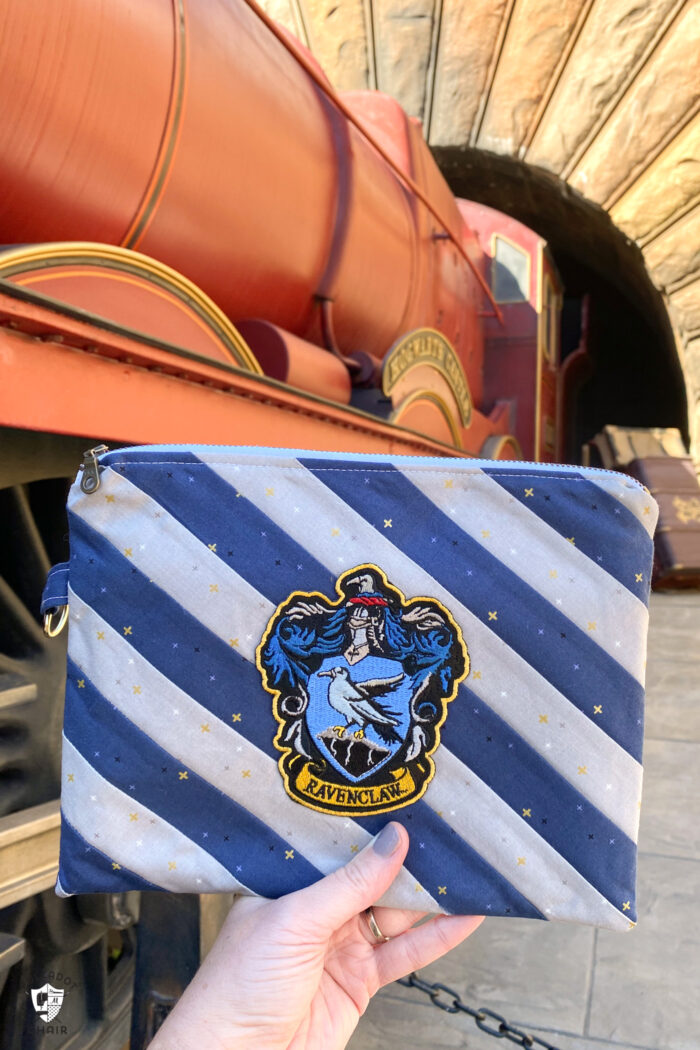 hand holding zip pouch in front of hogwarts express train