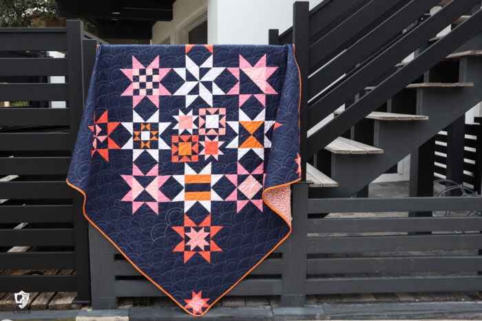 Navy, pink and orange modern star quilt on black staircase railing