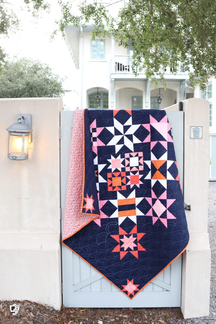 Navy, pink and orange modern star quilt on blue fence gate