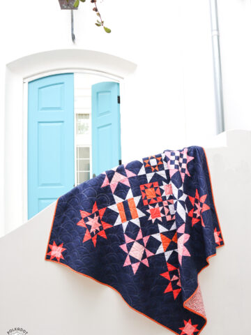 Navy, pink and orange modern star quilt on white fence