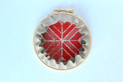 back of cross stitch ornament on white table