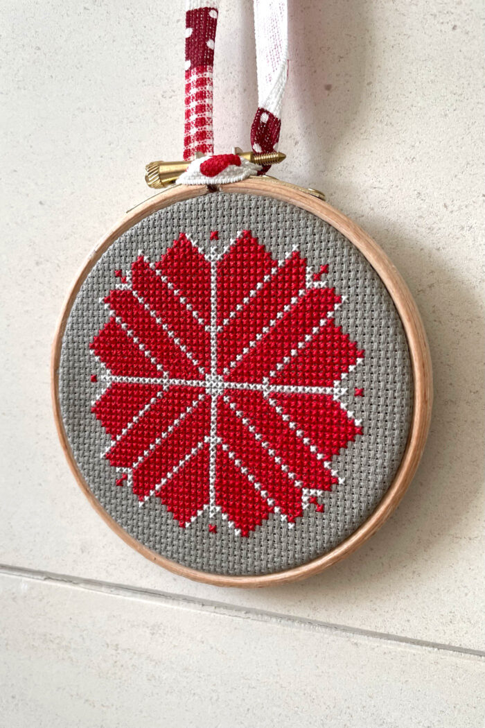 red, white and gray christmas ornament hanging on fireplace mantle