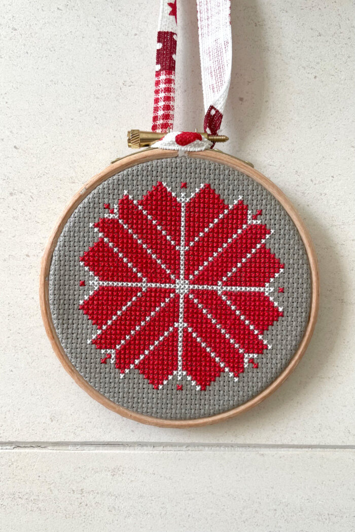 red, white and gray christmas ornament hanging on fireplace mantle