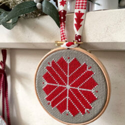 red, white and gray christmas ornament hanging on fireplace mantle