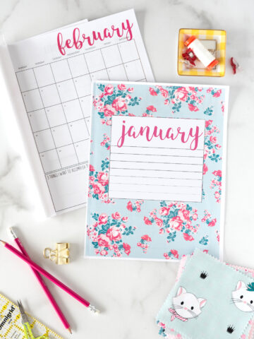 flat lay of printed planner pages and calendar with desk supplies on table