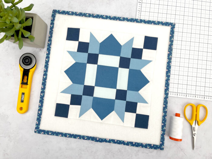Blue and white quilt block on cutting mat with sewing notions