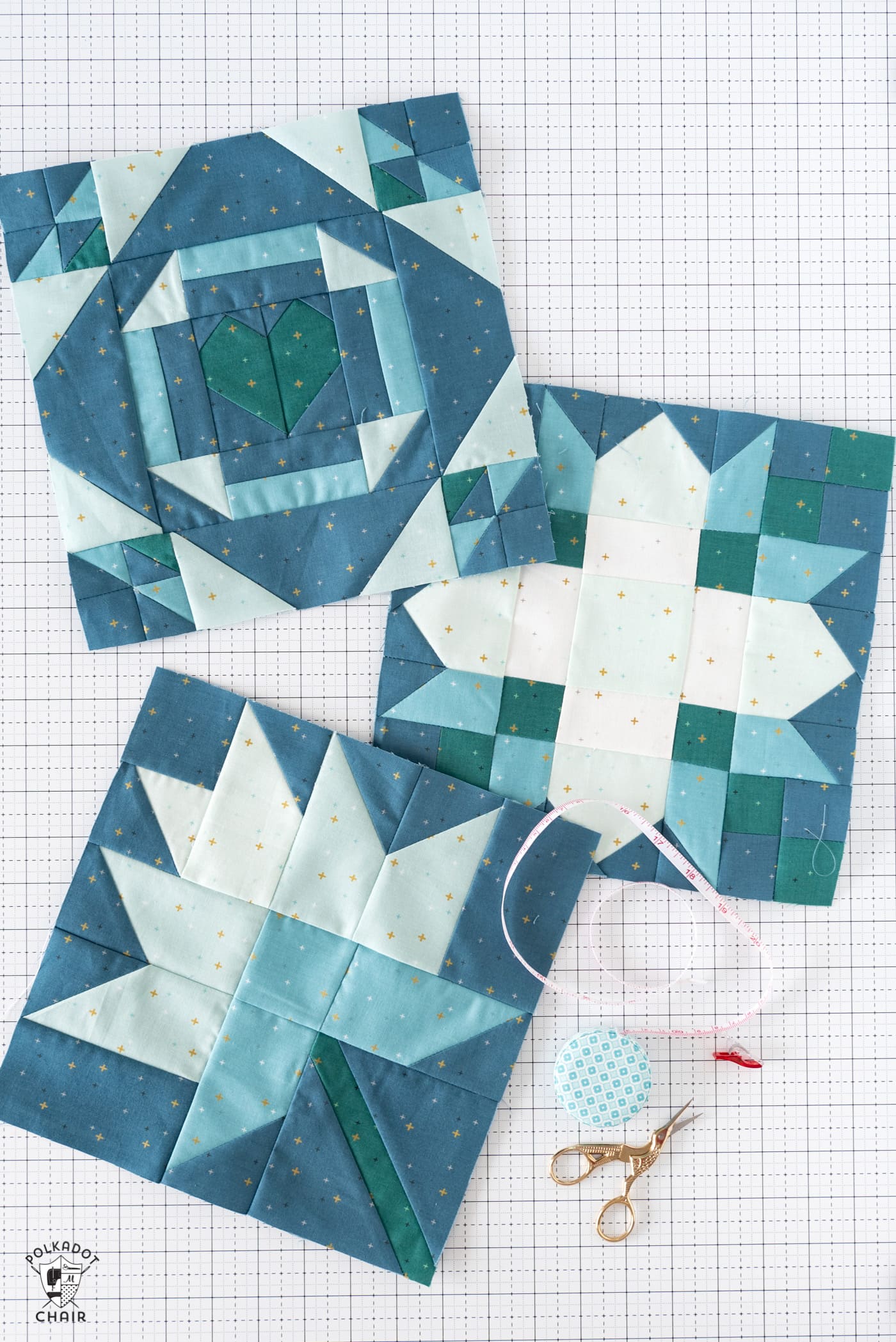 White blue and green quilt blocks on white cutting mat with folded fabrics