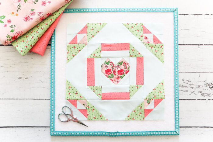 coral and green quilt block on white and blue cutting board