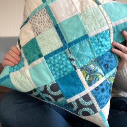 woman holding blue plaid quilted pillow