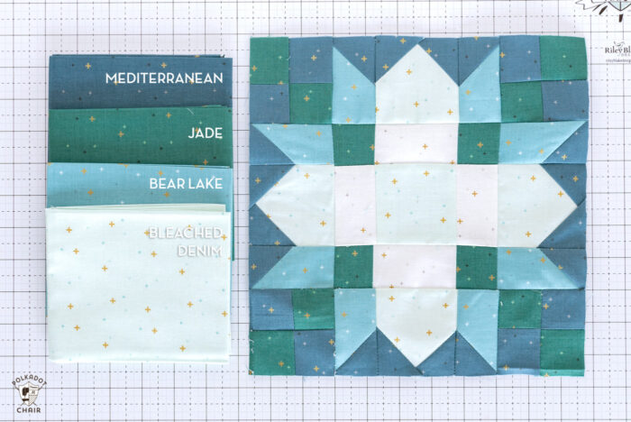 White blue and green quilt block on white cutting mat with folded fabrics